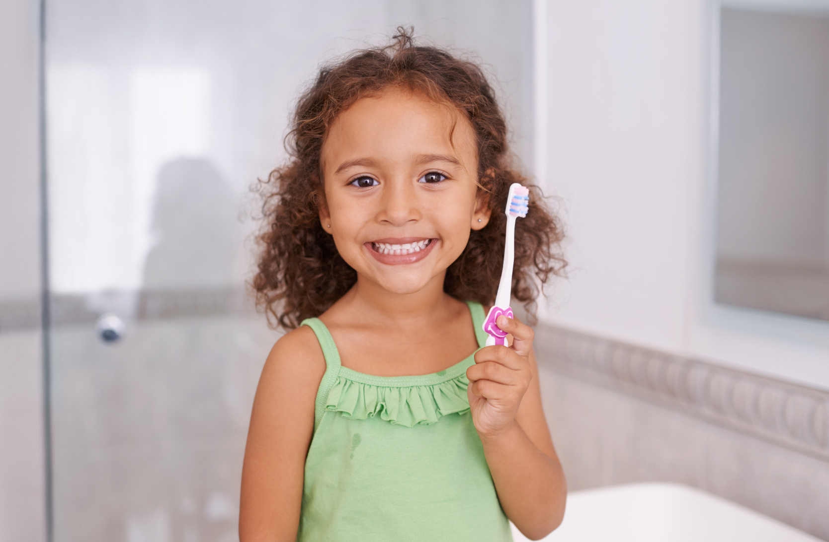 Young girl with big smile holding toothbrush