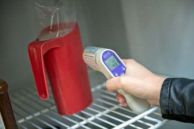 Public health inspector checking the temperature of milk in a fridge