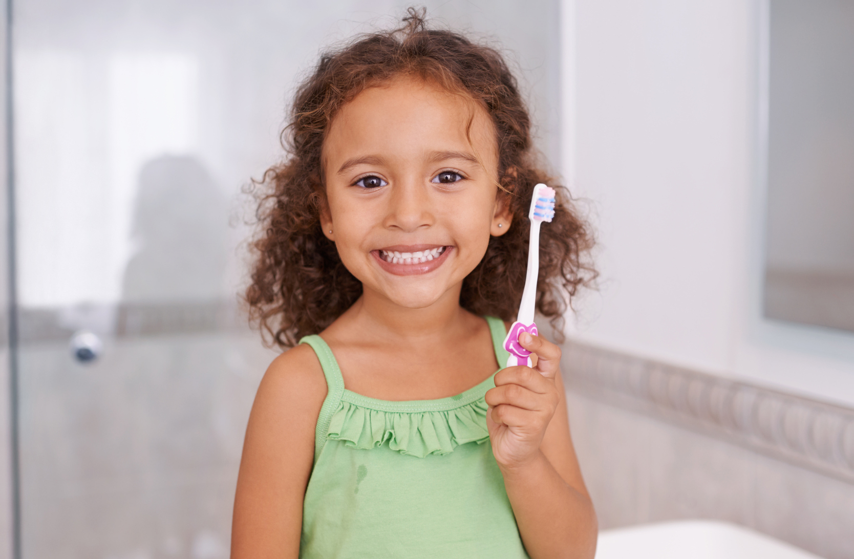 Girl smiling and holding up a toothbrush