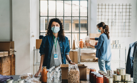 Photo of woman wearing mask working at foodbank representing a community setting