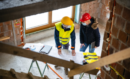 Picture of two men on a construction site wearing face coverings