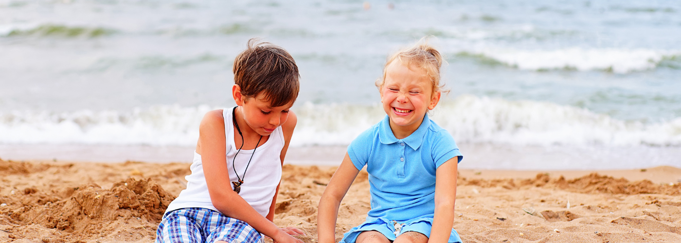 Two children sitting on a sandy beach