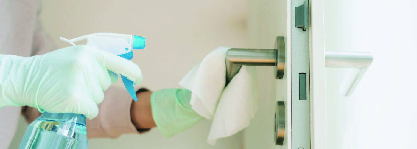 Person wearing gloves disinfecting a door handle