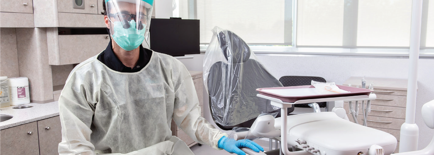 dental hygienist sitting in a dental clinic wearing personal protective equipment