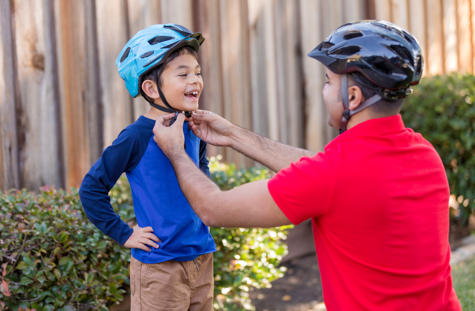 Picture of a dad buckling up his son's bike helmet