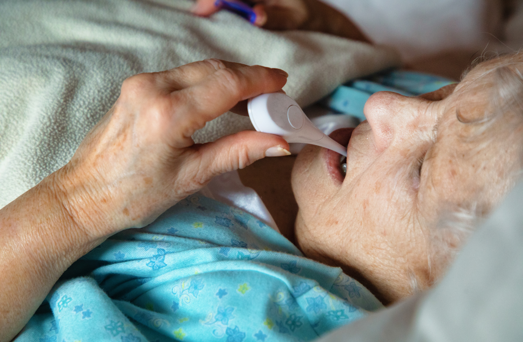 Elderly woman having her temperature taken in bed.