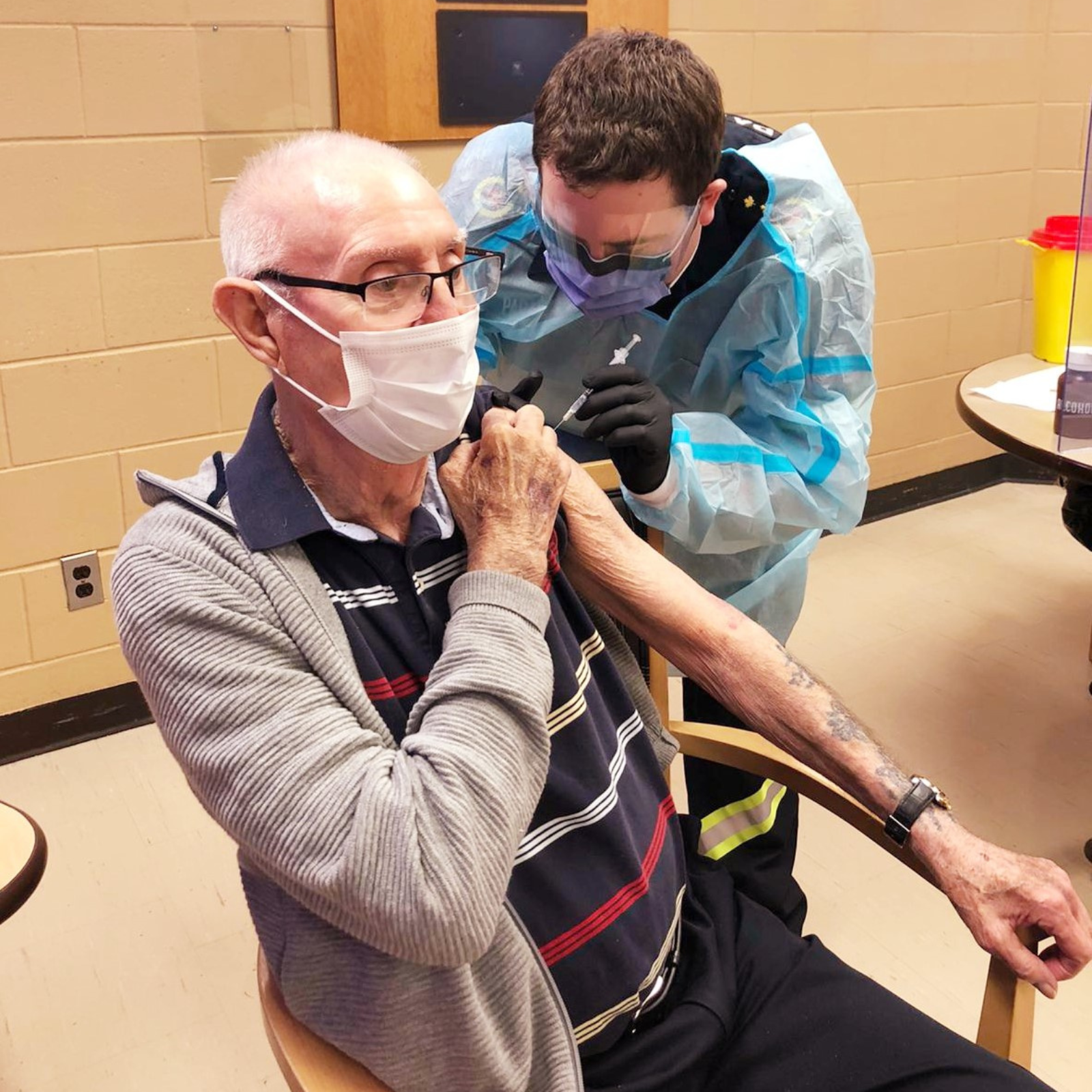 Elderly man receiving a vaccine from a healthcare worker in protective gear