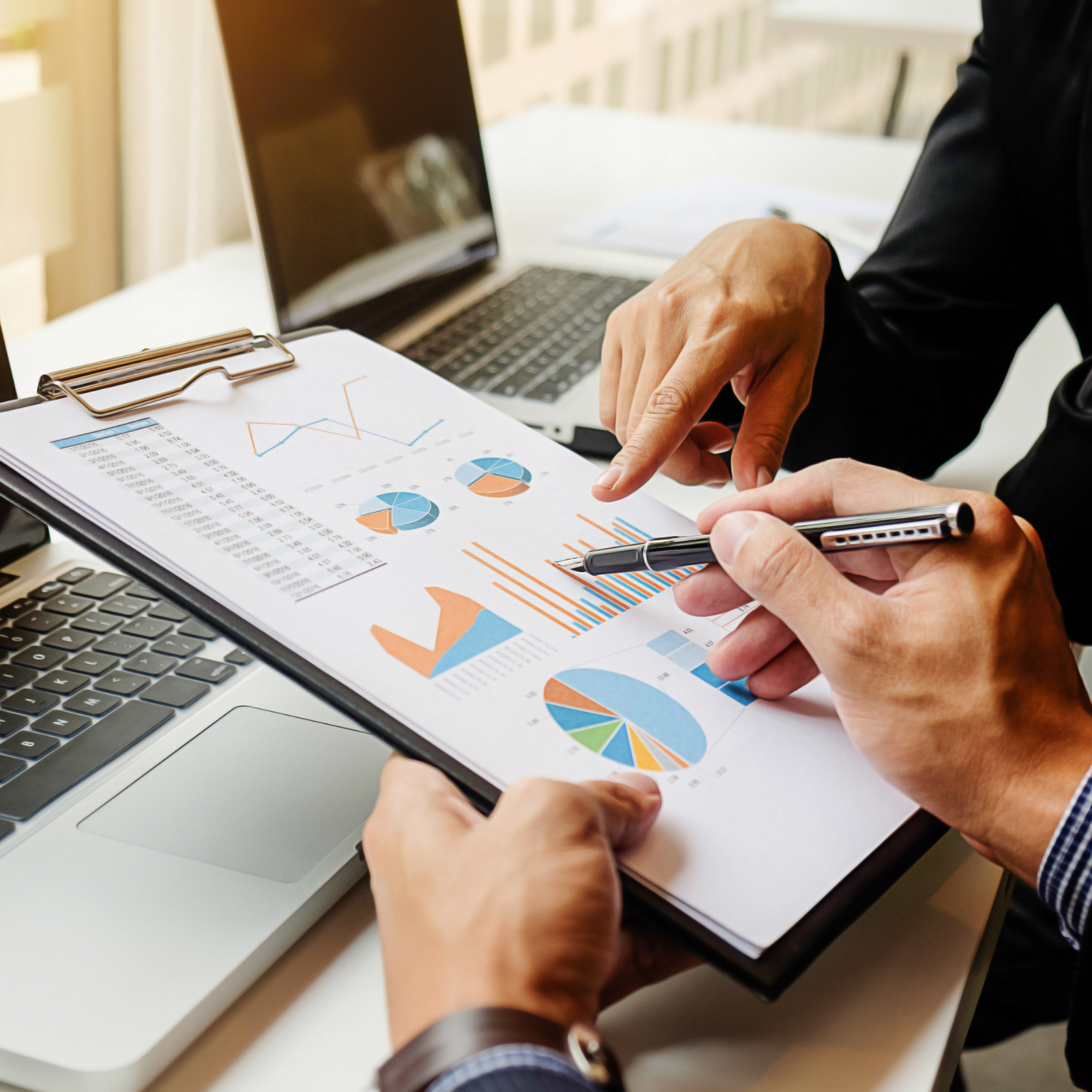 Close-up of two people reviewing colorful graphs and charts on a clipboard
