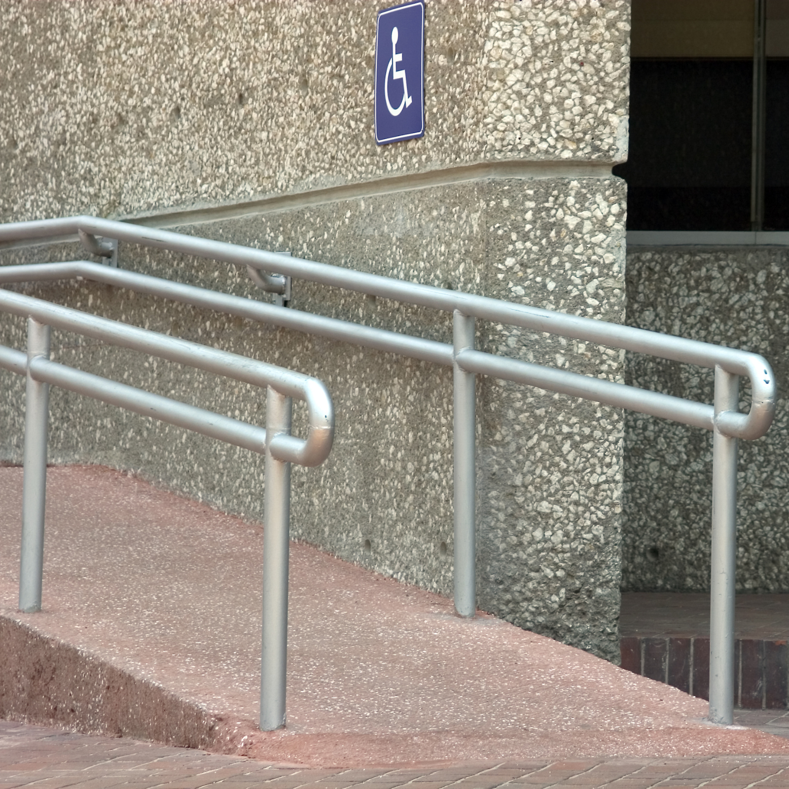 Wheelchair-accessible entrance with metal ramp and handrails