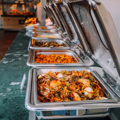 Open buffet with hot food trays filled with various dishes in a commercial food service setting