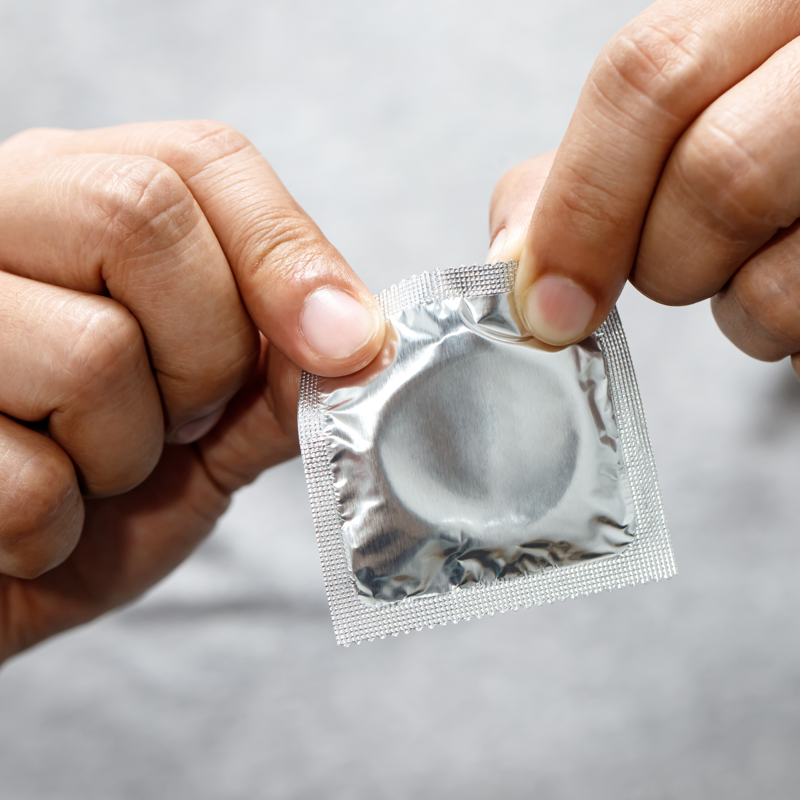 Person holding silver wrapped condom